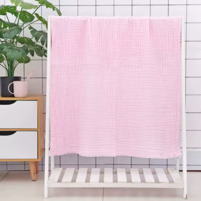 Couverture bébé en coton rose suspendu sur le support à vêtement.
