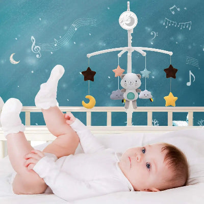 Mobile bebe musical en peluche suspendu sur le lit de bébé. Il joue avec les jouets devant lui.