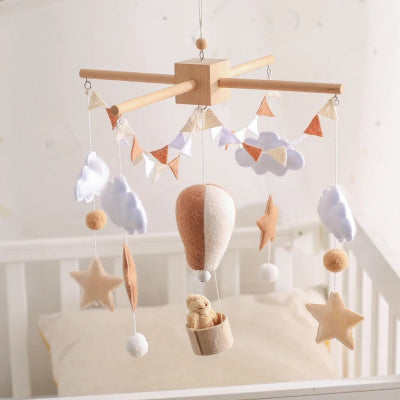 mobile pour lit bebe suspendu sur lit de bebe attirant attention sur les belles couleures patels et formes nuageux.