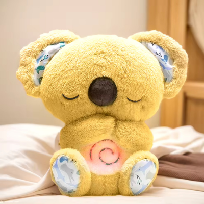 Peluche koala jaune déposé au coin d'un lit, son ventre illuminant la respiration humaine.