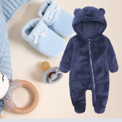 Pyjama bebe polaire bleu déposé sur un fond avec article de bébé.