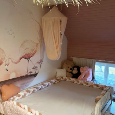 Tour de lit bebe blanc, gris et rose installé autour d'un lit, vue de loin.