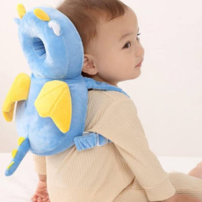 Bébé regarde sur le côté en portant le coussin de protection anti-choc dinausaure.