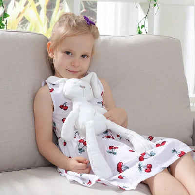 Petite fille assise sur un sofa, son doudou lapin apaisant sur elle.