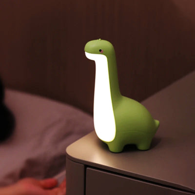 Veilleuse bébé dinosaure vert déposé sur une table de chevet illuminant la chambre.