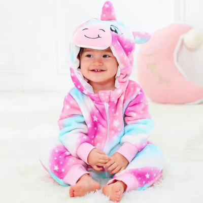 Petite fille souriante assis sur le tapis portant sa barboteuse câline mignonne licorne.