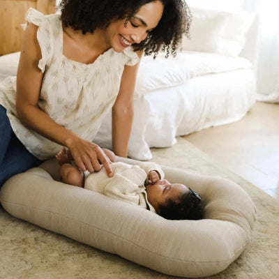 Bébé joue calmement dans son cocon bebe lit bionic. Maman souriante assis à côté.