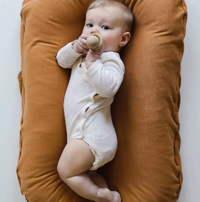 Bébé couché sur le côté, dans son cocon bebe multifonctionnel confortablement.