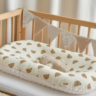 Un couffin bébé ourson placé sur un berceau de bébé qui est compatible avec presque n'importe quel lit.