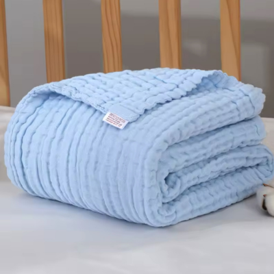 Couverture bébé bleu en coton plié déposé sur le lit.