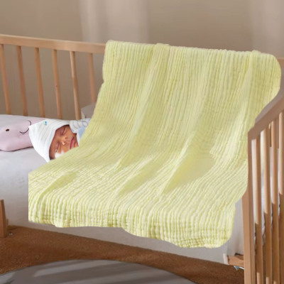 Bébé dort dans son lit couvert par sa couverture bébé jaune en coton.