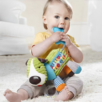 Petit garçon met l'anneau de dentition dans sa bouche, qui est attaché à son doudou bebe.