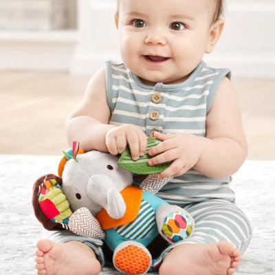 Petit enfant joue et s'épanouie en manipulant différentes composantes de son doudou bebe cozyrattle.