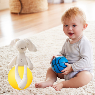 Bébé joue au ballon en compagnie de son doudou lapin apaisant.