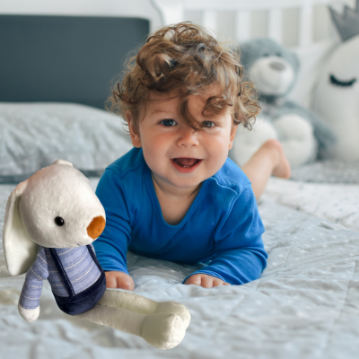 Bébé éclate de rire avec son doudou lapin bunny à ses côtés.