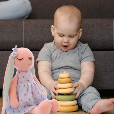 Bébé joue seul à côté de son compagnon doudou lapin Lili.