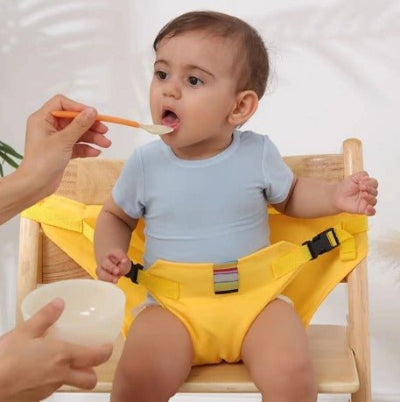 Bébé attaché avec son harnais chaise haute pendant qu'il mange.
