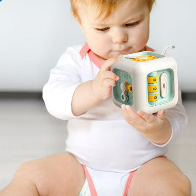 Bébé observe de près son jouet bebe cube interactif Montessori 6-en-1.