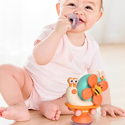 Bébé est distrait avec le jouet bebe eveil escargot rotatif à ventouse.
