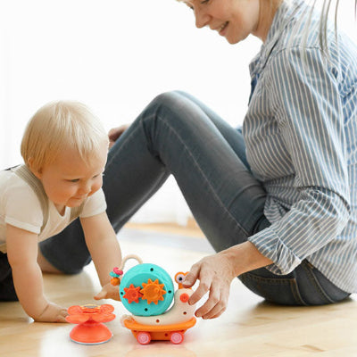 Maman avance jouet bebe eveil escargot rotatif à ventouse, pour que bébé joue avec.