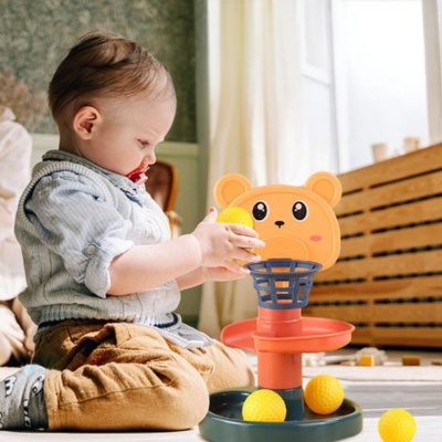 Petit garçon lance la balle dans son panier du jouet bebe eveil tour à balles 5 étages.