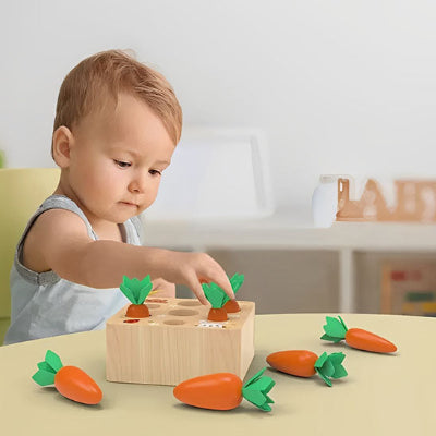 Petit garçon joue seul avec son jouet pour bebe 9 mois : jeu de tri de carottes.