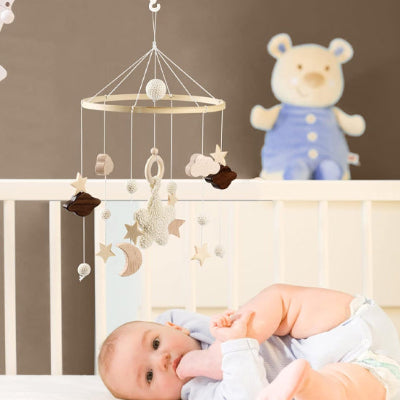 Bébé joue paisiblement dans son lit en présence de son mobile bebe nuage musical. 