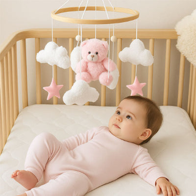 bébé fille calme attirée par le mobile bebe ourson rose fixe celui-ci.
