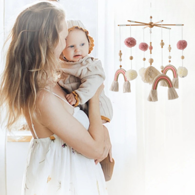 Maman fait découvrir au bébé le mobile pour lit bebe arc-en-ciel.