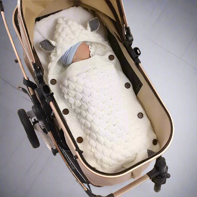 Bébé dort dans sa poussette portant son nid d'ange bebe acrylique blanc