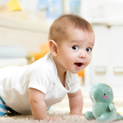 Bébé joue avec sa peluche T-Rex. 