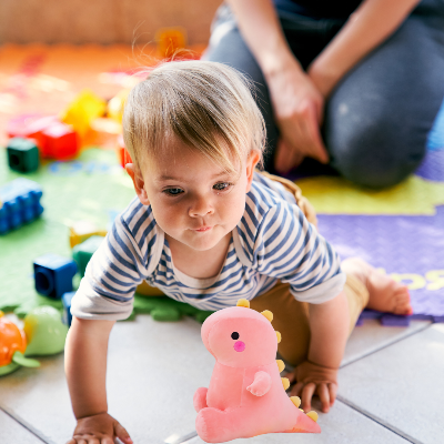Petit garçon joue avec sa peluche T-Rex cuddles déposé sur le plancher.