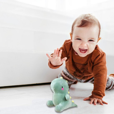 Bébé joue et essaye de prendre sa peluche T-Rex.