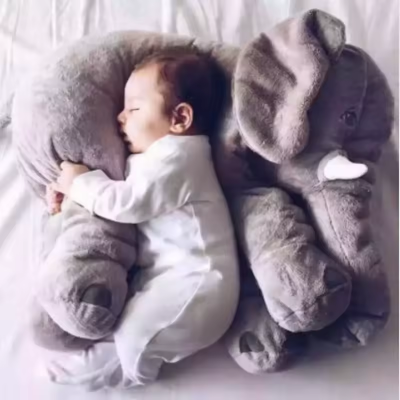 Bébé dort en serrant sa peluche elephant pour dormir.