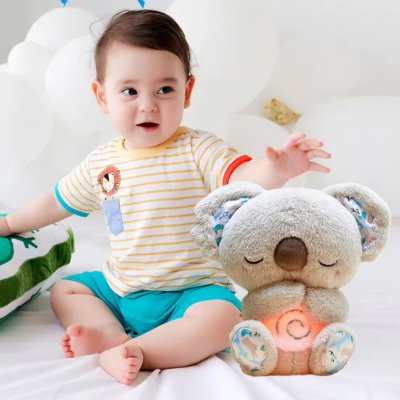 Petit garçon joue assis en présence de son compagnon, peluche koala grise.