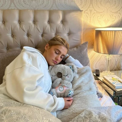 Grande fille se repose sur son lit collé à elle, sa peluche koala grise.