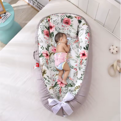 Bébé dort sur le côté dans son reducteur de lit fleur.