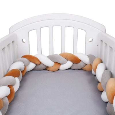 tour de lit tressé beige blanc et gris fait le perimètre sur les côtés de lit à barreaux.