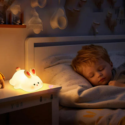 Veilleuse bébé Bunny Bliss diffusant une lumière douce pendant que bébé dort juste à côté.