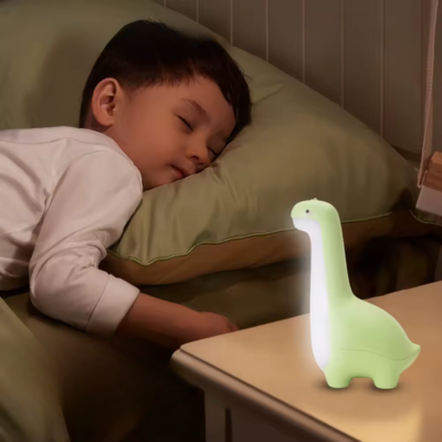 Enfant dort sereinement en présence de sa veilleuse bébé dinosaure vert.