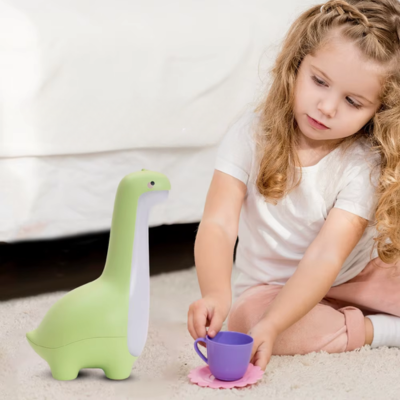 Une petite fille joue avec sa veilleuse bébé dinosaure vert.