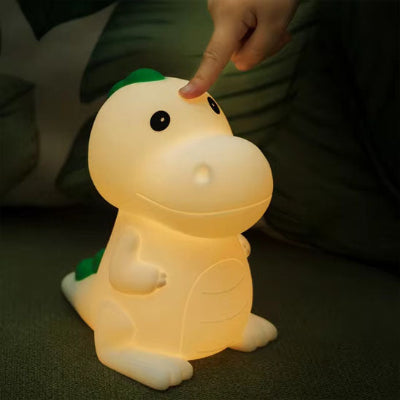 Un doigt en haut vient toucher veilleuse bébé Led Dinosaure pour changer intensité de la lumière.