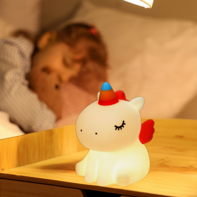 Veilleuse bébé Licorne diffusant une lumière douce près d’un enfant endormi.