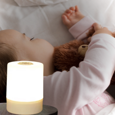Veilleuse bébé Lunella placée sur une table de chevet près d'un bébé qui dort.