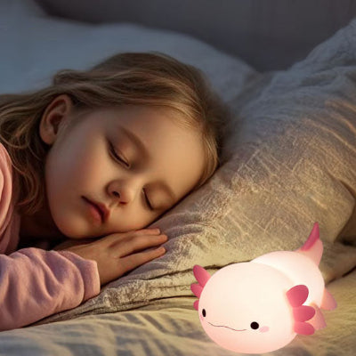 Scène nocturne avec la veilleuse enfant NémoRose diffusant une lumière douce près d’un enfant qui dort .