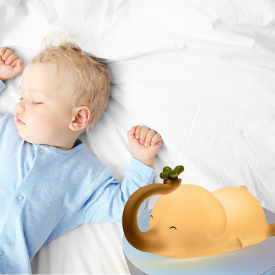 Petit enfant dort tranquillement à côté de sa veilleuse enfant éléphant douillet.