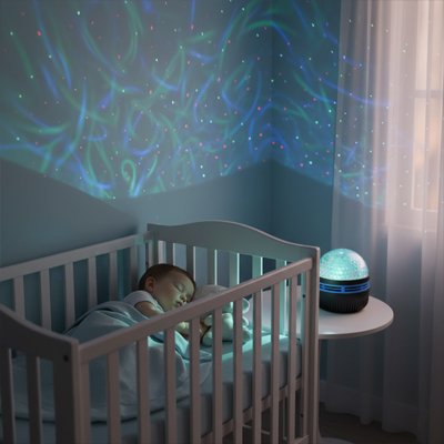 Bébé endormi sous les lumières de la Veilleuse projection Ciel Étoilé Magique.